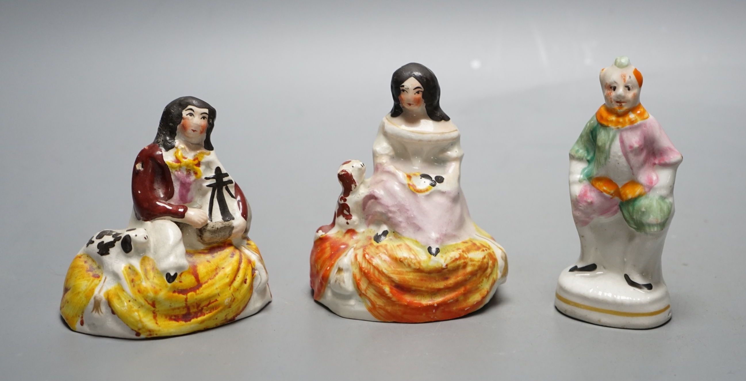 A pair of Staffordshire porcellaneous groups of children with a King Charles spaniel and a figure of Grimaldi the clown, c.1830-50 (3). Provenance - Dennis G. Rice collection., Clown 10 cms high.